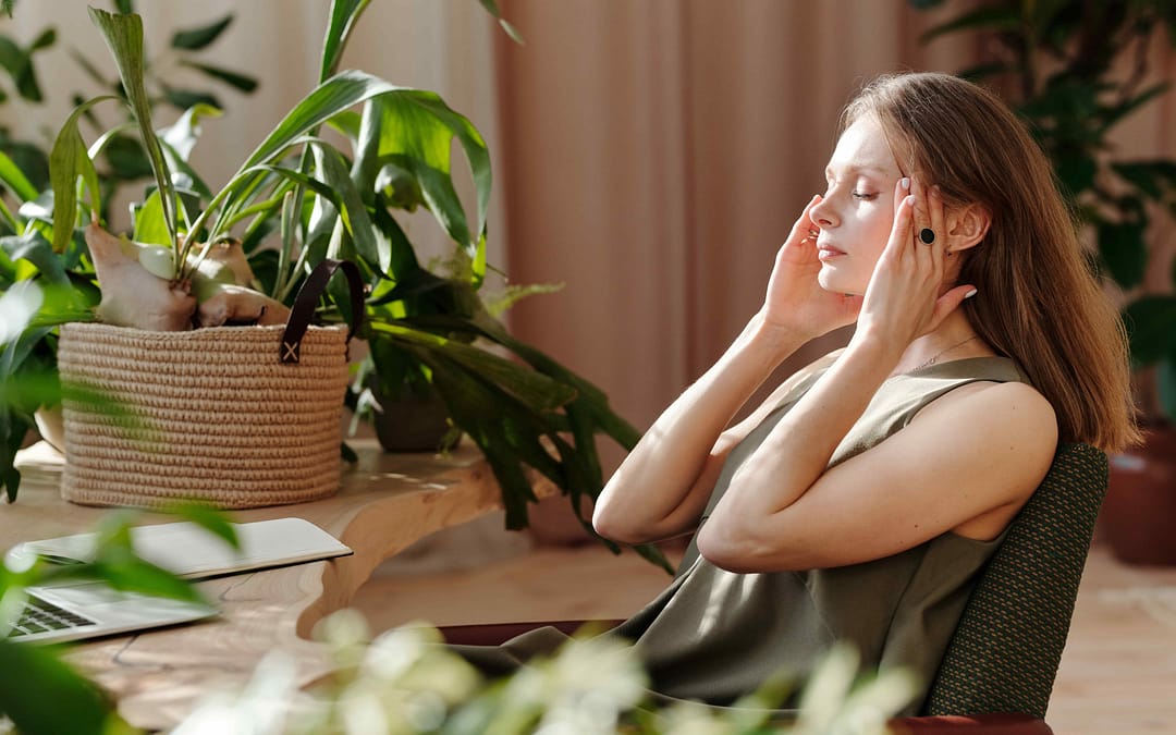 woman sitting indoors touching her forehead while doing NET therapy